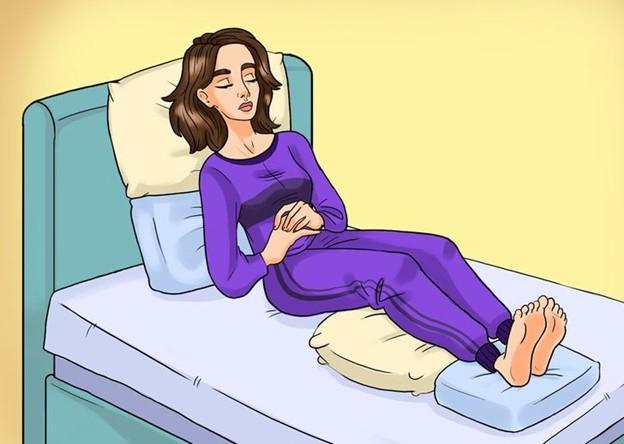 Nằm hơi nghiêng và để gôi kê dưới chân và lưng giúp giảm đau thắt lưng